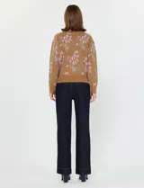 Buzo de tejido de punto azul marino con estampado floral en tonos terracota y verde azulado. Presenta cuello alto con cierre parcial frontal y puños y ruedo acanalados.