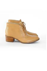 Botines color camel texturizado de cuero vacuno, con cordones frontales y tacón bloque de madera clara de 6 cm.