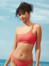 Traje de baño de dos piezas color coral con textura. El corpiño es bandeau asimétrico con un solo bretel y aro decorativo.