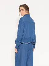 Camisa de denim liviano color azul, con ruedo curvo, canesú en forma de V en la espalda y acceso mediante botones.