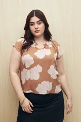 Blusa color marrón con estampado floral en tonos blanco y rosa, de corte holgado y mangas cortas.