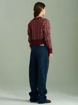 Cardigan de punto color borgoña con diseño geométrico en blanco y detalles en azul. Tiene cuello redondo, cierre frontal con botones rojos y mangas largas con puños acanalados.