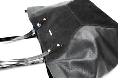 Bolso grande negro con paneles de gamuza natural suave al centro y 100 % cuero en los laterales. Presenta dos asas de mano con detalles estampados. Diseño moderno y espacioso, combinando texturas elegantes.