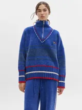 Sweater azul con cuello alto con medio cierre, textura tipo terciopelo y puños acanalados.