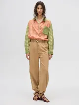 Mono largo de jean celeste con corte holgado, cintura elastizada con cordón ajustable, sin mangas, cuello camisero y cierre frontal con botones. Presenta bordados de motivos playeros en el pecho.