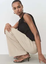 Pantalón largo de mujer color beige, de corte ancho y tiro alto, con cintura elástica y lazo ajustable.