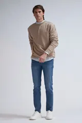 Sudadera de tejido liso color beige, con cuello redondo y puños y ruedo acanalados. Se lleva superpuesta a una camisa de cuadros celestes y blancos.