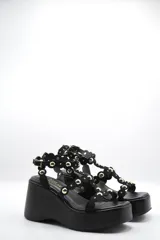 Sandalias negras de plataforma con tiras de gamuza decoradas con esferas doradas.