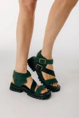 Sandalias de cuero verde oscuro con tiras cruzadas y hebillas doradas. Suela track negra.