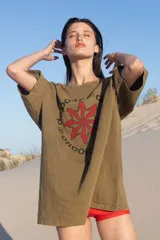 Remera verde militar de corte amplio con estampa en el frente con texto en español y siluetas rojas.