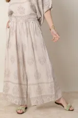 Pantalón palazzo de lino color crudo con estampado floral al tono, tiro alto y cintura elastizada.