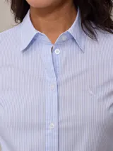 Camisa celeste a rayas verticales blancas, de manga 3/4 con puños arremangados y cuello clásico.