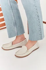 Mocasines de cuero color marrón claro con costuras a la vista.