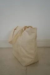 Bolso tote de lona color crudo con asas de hombro. Decorado con parches bordados de motivos playeros y pañuelo rojo estampado atado a una de las asas.