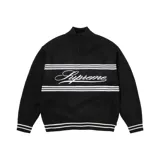 Sweater de punto negro con cierre de cremallera corto en el cuello y rayas horizontales blancas. Presenta la palabra 'Supreme' bordada en blanco en el pecho.
