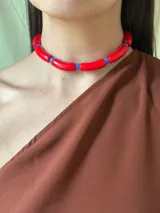 Gargantilla con cuentas de tubo acrílicas rojas y cristales checos azules. Se cierra con cadena de acero quirúrgico y ganchito para regular el largo.