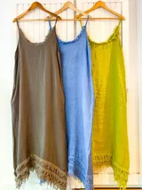 Vestido de lino con breteles finos y escote redondo, corte recto y ruedo con flecos.