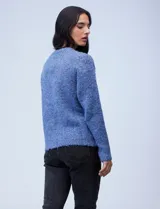 Buzo de tejido melange color beige con puntos oscuros, cuello redondo y manga larga.