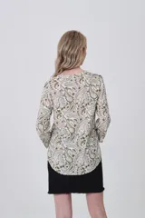 Camisa de manga larga con cuello mao y estampado paisley en tonos blanco, verde oliva y rosado. Presenta un calce holgado y bolsillos frontales.