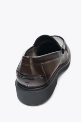 Zapato plano tipo mocasín color marrón, con detalle de antifaz y fruncido delantero. Suela ancha con acabado en punta redonda.