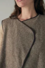 Chaleco marrón con solapas amplias y terminaciones envivadas. Diseño reversible y sin mangas.