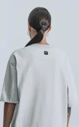 Remera gris de corte crop y calce oversize, con hombros caídos y cuello redondo.