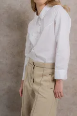 Camisa blanca de algodón con cuello tipo masculino, abotonadura central, manga larga y puños con botones. Canesú y cuello bordado con cadeneta a contratono.