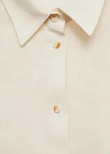 Camisa blanca de lino con cuello clásico, manga corta y cierre frontal con botones.