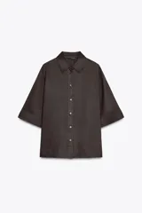Camisa marrón de corte recto, con cuello solapa, manga corta y cierre frontal con botones.