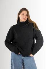 Sweater negro tejido en punto arroz, con cuello alto, mangas largas y silueta holgada.