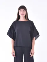 Blusa negra de mangas cortas con volados y escote redondo.