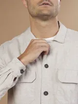 Camisa color verde militar de manga larga con cuello clásico, cierre frontal con botones y dos bolsillos de parche en el pecho.