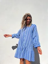 Vestido camisero corto celeste con bordado de flores blancas, corte recto y mangas largas.