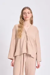 Blusa color beige de manga larga, con cuello en V y cierre frontal con botones.