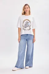 Remera blanca de corte amplio con estampado de Cenicienta y la frase 'The Right Shoe Makes the Difference'.