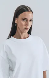 Remera blanca de algodón con corte crop, calce oversize, hombros caídos y cuello redondo.