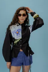 Camisa negra con estampado de flores y libelulas, con cuello clásico, mangas largas abullonadas y fruncido tipo corset.