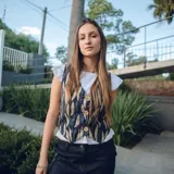 Chaleco corto color crema con escote en V, sisa redonda y cierre delantero con botones.