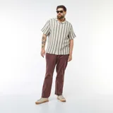 Camisa de manga corta con rayas verticales color crema y gris. Tiene cuello clásico y cierre frontal con botones.