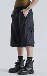 Pantalón negro con corte ancho, bolsillos laterales con solapa y detalle de cierre a la altura de la rodilla para convertirlo en short.