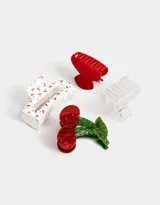 Set de cuatro broches para el pelo con forma de pinza. Incluye un broche blanco con estampado de cerezas, uno transparente, uno rojo y uno con forma de cereza.