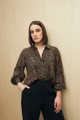 Camisa marrón con estampado animal print negro, de calce relajado, cuello clásico, abotonadura frontal y mangas largas con puños camiseros.