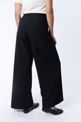 Pantalón de vestir negro de corte palazzo con pinzas en la cintura y bolsillos laterales.