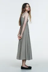 Vestido midi de tirantes con escote cuadrado y falda amplia con godets, confeccionado en tela con estampado de cuadros vichy en blanco y negro.