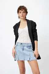 Minifalda de jean tiro bajo color negro con silueta evasé, dos tajos delanteros y ruedo desflecado.