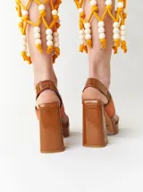 Sandalias de plataforma color naranja con detalles en marrón. Tienen tiras anchas sobre el empeine y el tobillo, y un tacón cuadrado alto.