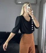 Blusa negra de crepé de lino con escote en V, mangas 3/4 con hombreras y detalle fruncido en los hombros. Se ata en la espalda con tiritas.