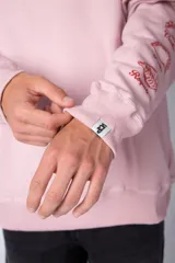 Buzo negro de corte oversize con cuello redondo y mangas largas. Presenta un pequeño logo estampado en el pecho y un diseño de empanadas y textos en la manga.