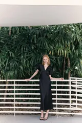 Vestido midi negro satinado con escote pico, pliegues en el busto y mangas cortas. Cintura entallada y cierre lateral con cremallera oculta.