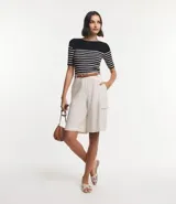 Blusa de punto con textura acanalada, escote barco y mangas 3/4. Diseño a rayas horizontales blancas y negras.